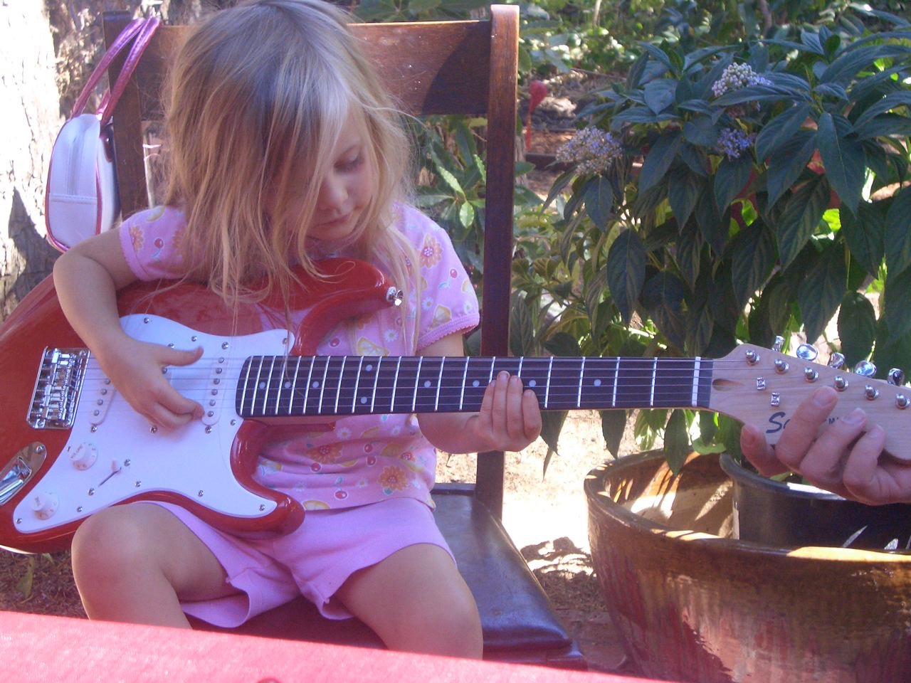 Milabella as a young musician, playing a red electric guitar